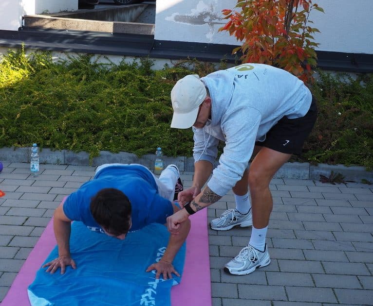Jannis korrigiert die Übungsausführung einer Kundin